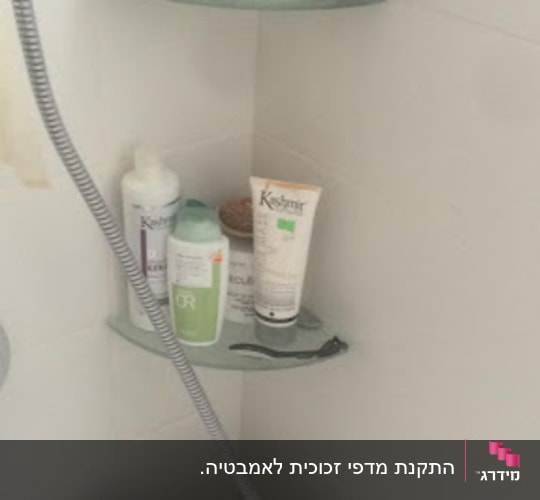 מדפי זכוכית בפינת מקלחת עם מוצרי טיפוח